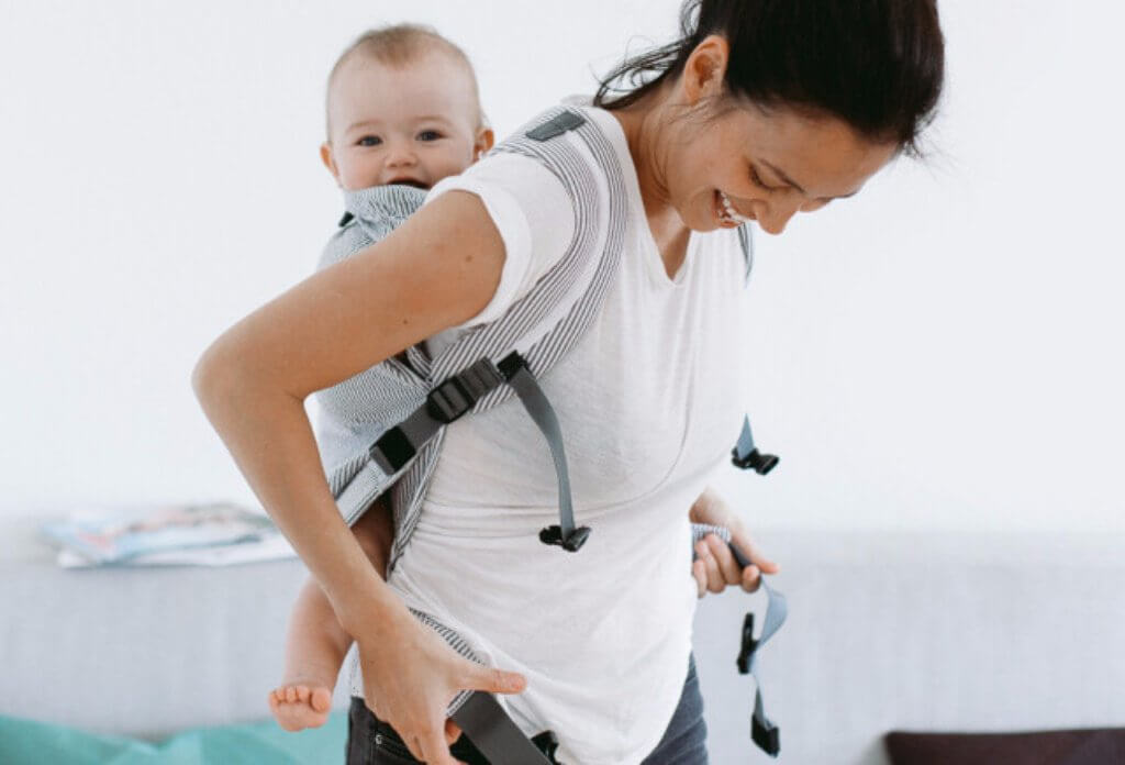 Mom carries happy baby in Weego Original Infant Carrier