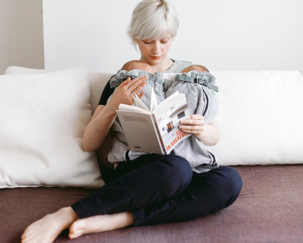 Young mom reading a book with twins in Weego TWIN carrier